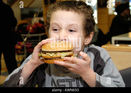 Petit boy eating hamburger Big Mac de Mcdonald's England UK Banque D'Images