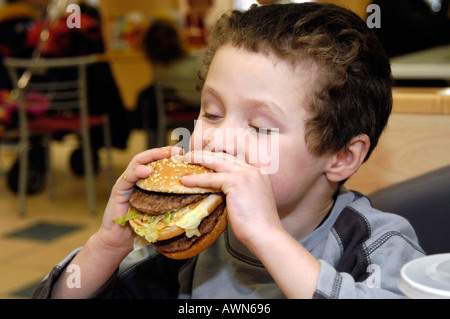 Petit boy eating Mcdonald's Big Mac, England UK Banque D'Images