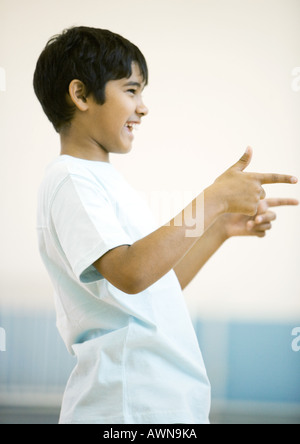 Teen boy pointing avec deux mains, smiling Banque D'Images