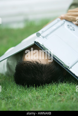 Homme étendu dans l'herbe avec coffre covering face Banque D'Images