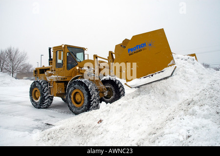 De grandes machines déneige efface shopping mall stationnement après une tempête de neige Banque D'Images