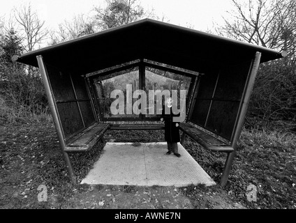 Le noir et blanc granuleux de l'image urbaine, jeune garçon dans un abri couvert de graffitis Banque D'Images