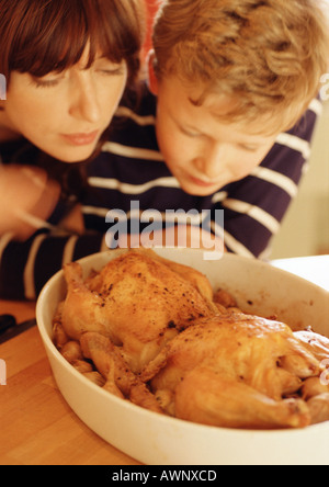 Femme et enfant regardant les poulets dans cocotte Banque D'Images