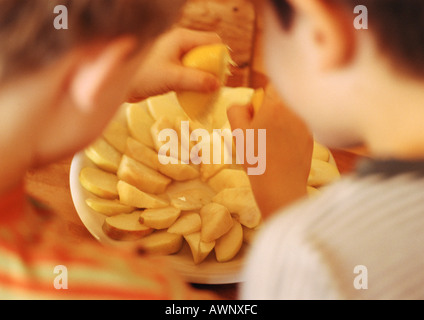 Deux enfants, l'un serrant les citrons sur les tranches de pommes, les enfants floue en premier plan, vue arrière Banque D'Images