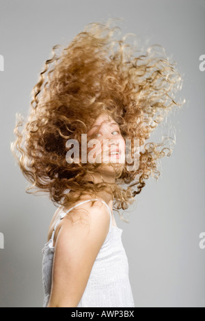 Jeune femme, ses longs cheveux bouclés volant par l'air Banque D'Images