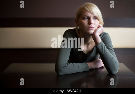 Femme blonde à la triste assis à une table dans un bar Banque D'Images