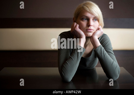 Femme blonde à la triste assis à une table dans un bar Banque D'Images