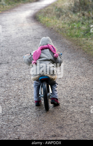 Jeune enfant cycliste vers le bas un chemin d'asphalte en hiver Banque D'Images