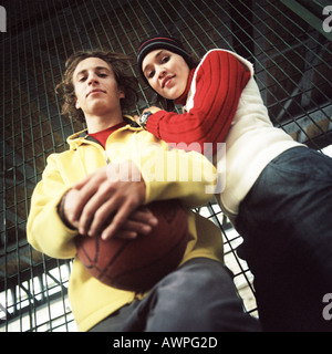 Jeune homme avec le basket-ball, jeune femme appuyée sur son épaule, low angle view Banque D'Images