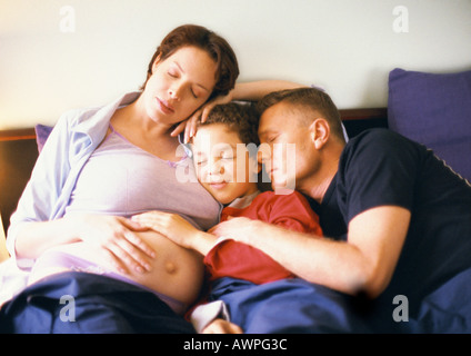 Pregnant woman sitting avec l'homme et l'enfant au lit Banque D'Images