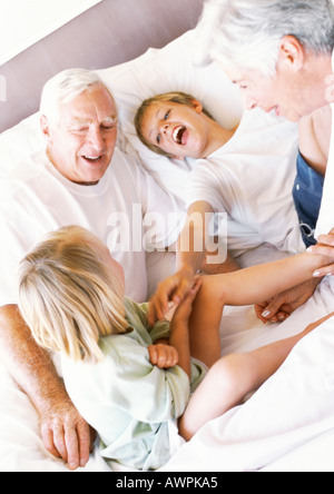 Les grands-parents et les enfants jouant sur bed, smiling Banque D'Images