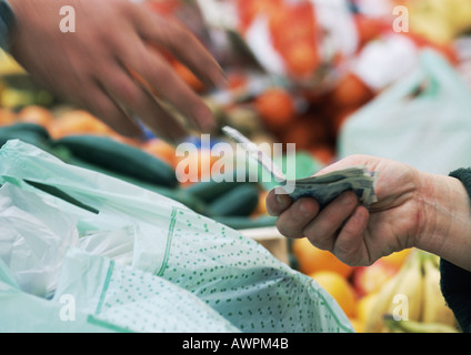 Mains d'échanger de l'argent dans le marché, close-up, blurred motion Banque D'Images