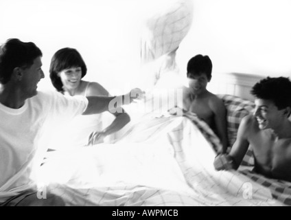 Family having pillow fight in bed, b&w Banque D'Images