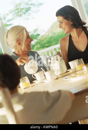 Deux femmes et un enfant de prendre le petit déjeuner, vue latérale Banque D'Images