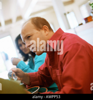 Couple assis à table, side view Banque D'Images