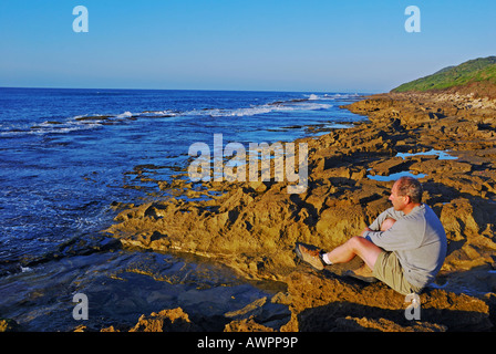 Homme assis au bord de la mer, paradis du pêcheur à Sainte-Lucie, Afrique du Sud Banque D'Images