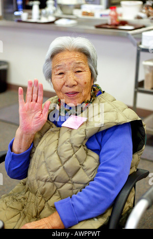 Senior Asian woman smiles et des vagues à l'appareil photo. Banque D'Images