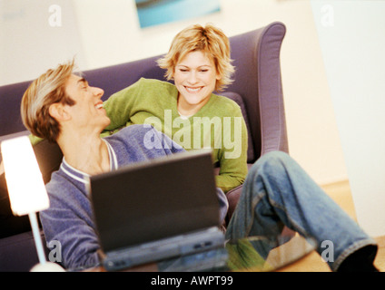 Couple smiling, using laptop Banque D'Images