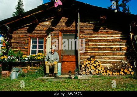 Un homme âgé assis devant sa maison de notation, Brooks Range, Alaska, USA Banque D'Images