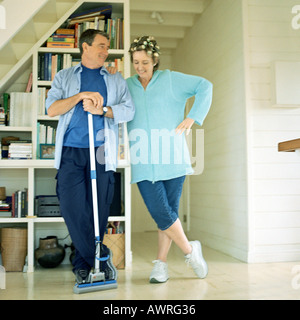 Mature couple côte à côte, man holding broom Banque D'Images