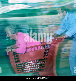 Homme mature femme poussant dans votre panier, blurred motion Banque D'Images