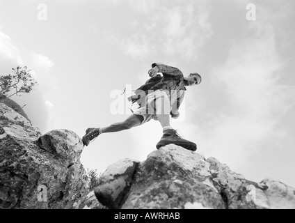 L'homme en franchissant les roches, low angle view, b&w. Banque D'Images