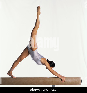 Jeune gymnaste sur poutre d'effectuer, side view Banque D'Images