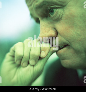 Extreme close-up of man biting pouce, side view, cool ton. Banque D'Images