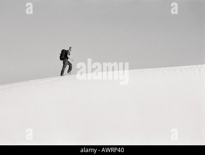 Homme randonnée le long de crête de dune, side view, b&w Banque D'Images