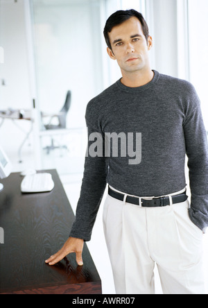 Businessman standing with hand on table Banque D'Images