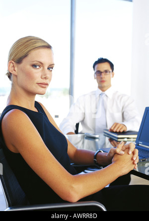 Businessman and woman sitting in office, portrait Banque D'Images