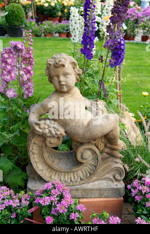 Déco jardin, putto garçon est assis sur une colonne en face de delphinium et monarda Banque D'Images