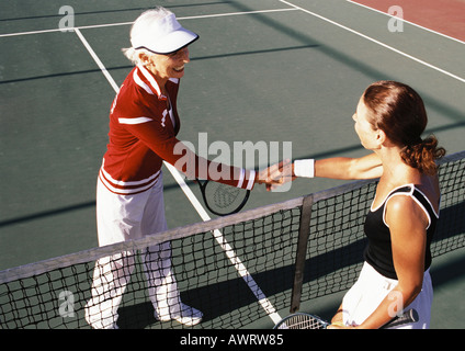 Deux femmes matures se serrer la main sur le court de tennis Banque D'Images