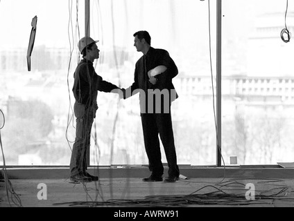 Deux hommes avec des casques, une poignée de main, b&w Banque D'Images