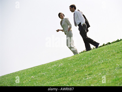 Businessman and woman walking on grass Banque D'Images