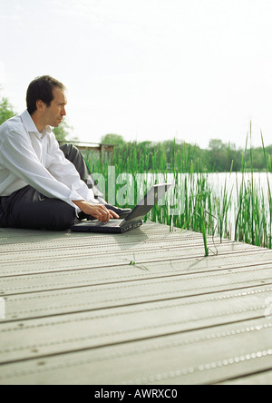 Homme assis à l'extérieur avec un ordinateur portable Banque D'Images