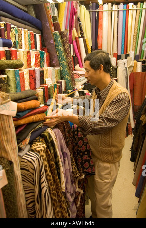 dh Western Market SHEUNG WAN HONG KONG tissu asiatique textile shop china worker chinois vendant des rouleaux de soie matériau tissu shopping assistant Banque D'Images