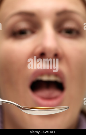 Jeune Femme prenant une cuillerée de médecine Banque D'Images