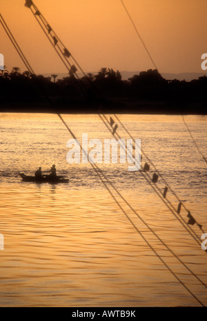 Deux hommes dans un bateau à rames, sur le Nil au temps du soir. Banque D'Images