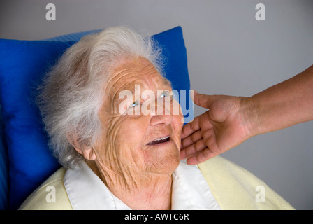 Sourire de contentement femme âgée avec réconfortante main de soignant Banque D'Images