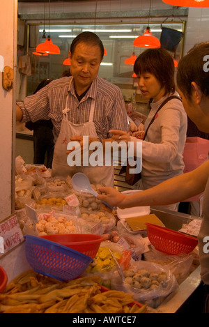 Dh shopping chinois HONG KONG Sham Shui Po et le client vendeur boutique Snack food stall display Chine femme Banque D'Images