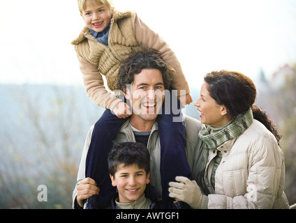Femme adulte et adulte homme debout à l'extérieur avec deux enfants, petite fille sur les épaules de l'homme, portrait Banque D'Images