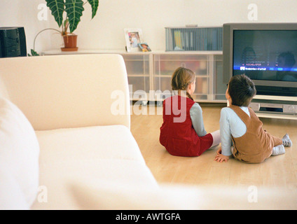 Petit garçon et fille assis ensemble sur parquet à à plat, vue arrière Banque D'Images