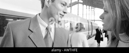 Couple talking on train platform, tête et épaules, b&w, vue panoramique Banque D'Images