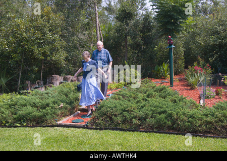 Un couple marche sur des tremplins à travers un jardin à la pelouse Banque D'Images