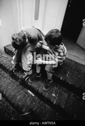 Deux enfants dans les escaliers, l'un tenant la tête dans les mains, b&w Banque D'Images