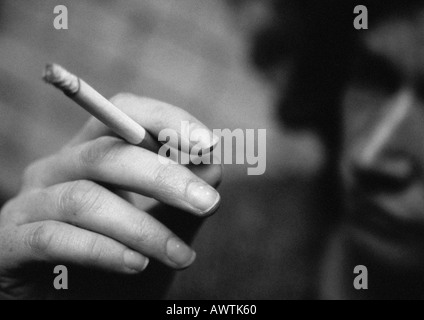 Woman's hand holding cigarette, close-up, brouillées, b&w Banque D'Images