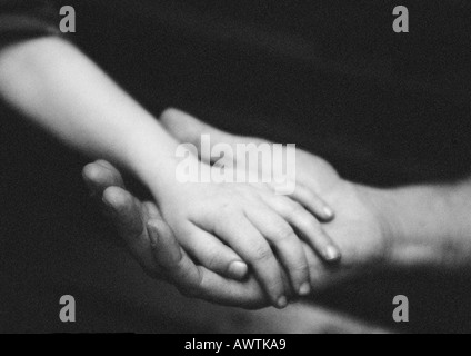 Mains adultes tenant la main de l'enfant, close-up, b&w Banque D'Images