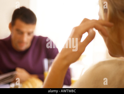 Femme assise en face de l'homme à table, vue arrière.
