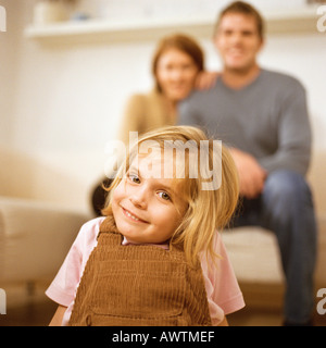 Little girl smiling at camera, les parents derrière elle Banque D'Images